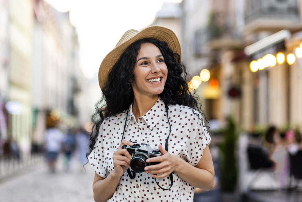 A woman wearing a hat and holding a camera